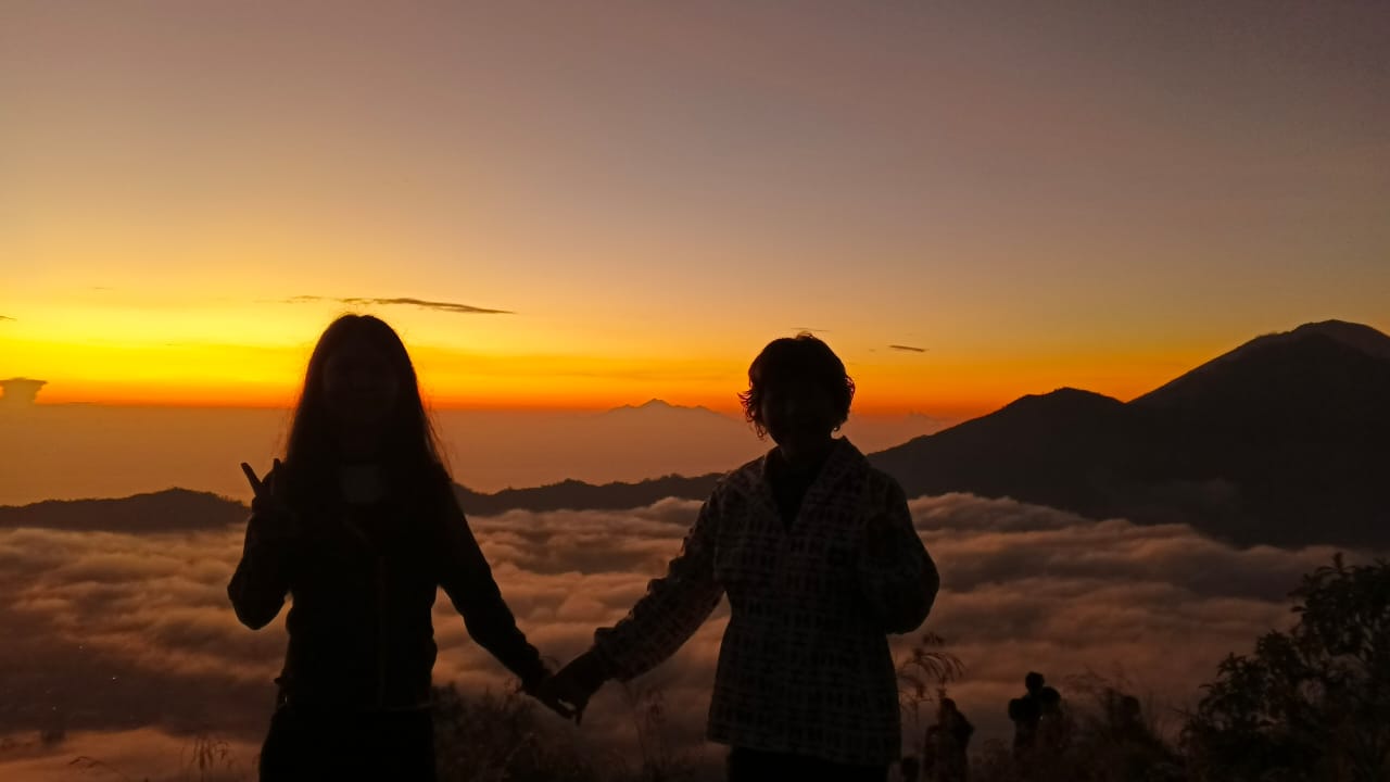 Travelers watching sunrise above the clouds at Mount Batur